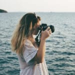 Woman with camera shooting on the beach